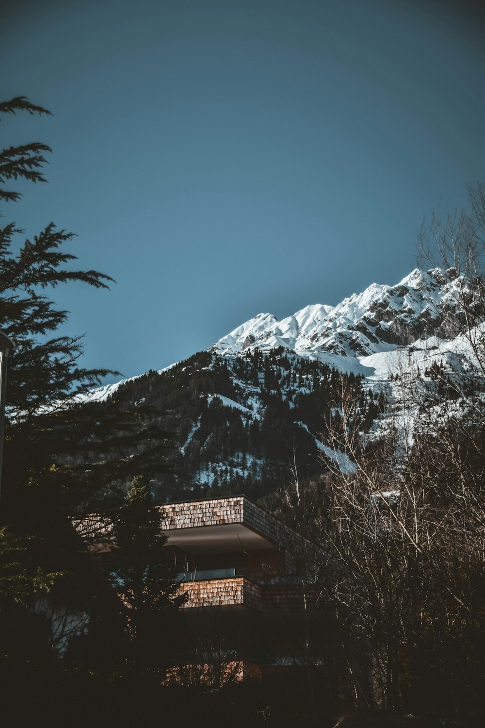 Edificio de hormigón marrón cerca de la montaña cubierto de nieve durante el día