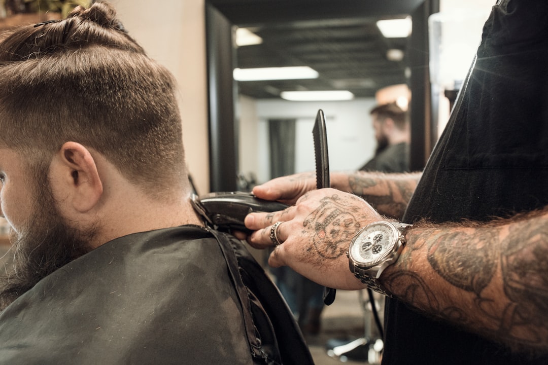 Dustin, our talented and inked up barber at Whiskey Neat Barbershop, working on a fade and beard trim.