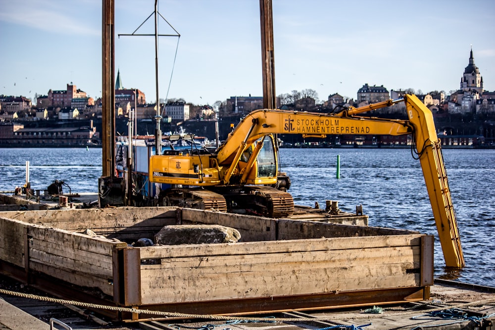 yellow excavator on top of metal platform above sea