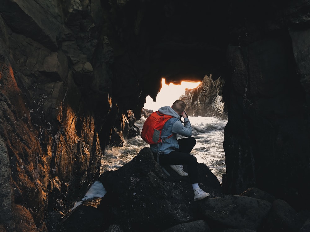 Ein Mann, der auf einem Felsen sitzt und auf den Ozean hinausschaut