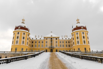 landscape photography of pathway leading to yellow building under gray sky