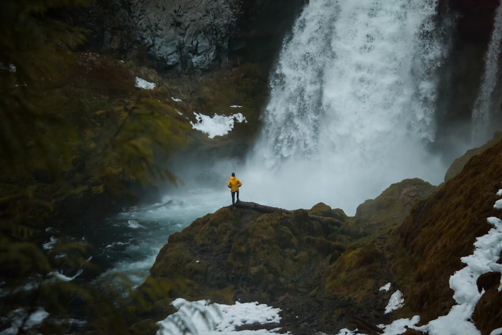 man standing beside waterfalls