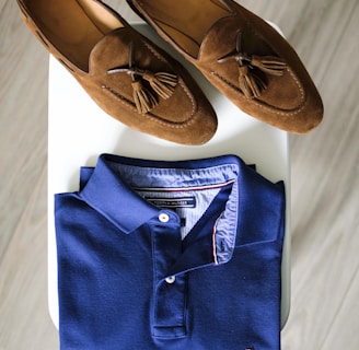 pair of brown loafers and blue polo shirt