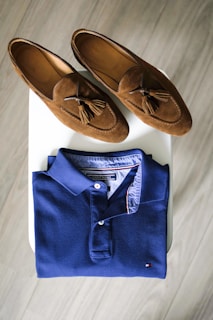 pair of brown loafers and blue polo shirt