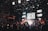 A lively concert scene with a band performing on stage, surrounded by an enthusiastic crowd. Confetti fills the air as bright stage lights illuminate the musicians and the audience. The atmosphere is vibrant, with people capturing the moment on their phones.