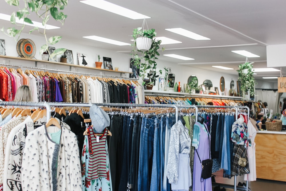 Des vêtements de couleurs assorties accrochés à l’intérieur d’un grand magasin avec des lumières allumées