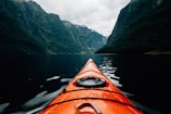 orange canoe on lake surrounding with mountain at daytime