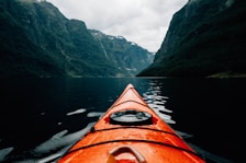 orange canoe on lake surrounding with mountain at daytime