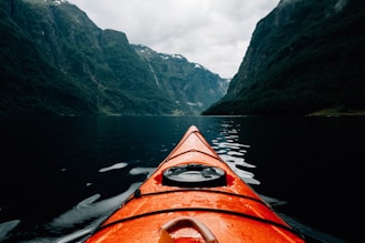 orange canoe on lake surrounding with mountain at daytime