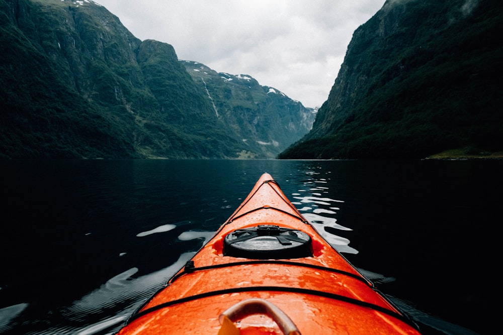 orange canoe on lake surrounding with mountain at daytime