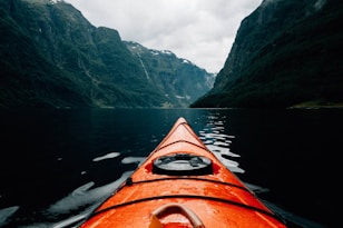 orange canoe on lake surrounding with mountain at daytime