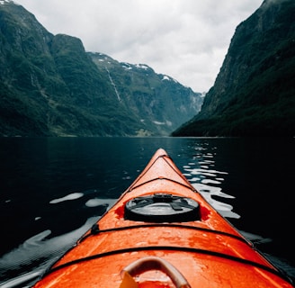 orange canoe on lake surrounding with mountain at daytime