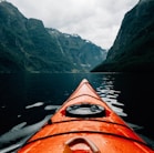 orange canoe on lake surrounding with mountain at daytime