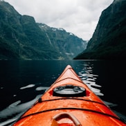 orange canoe on lake surrounding with mountain at daytime