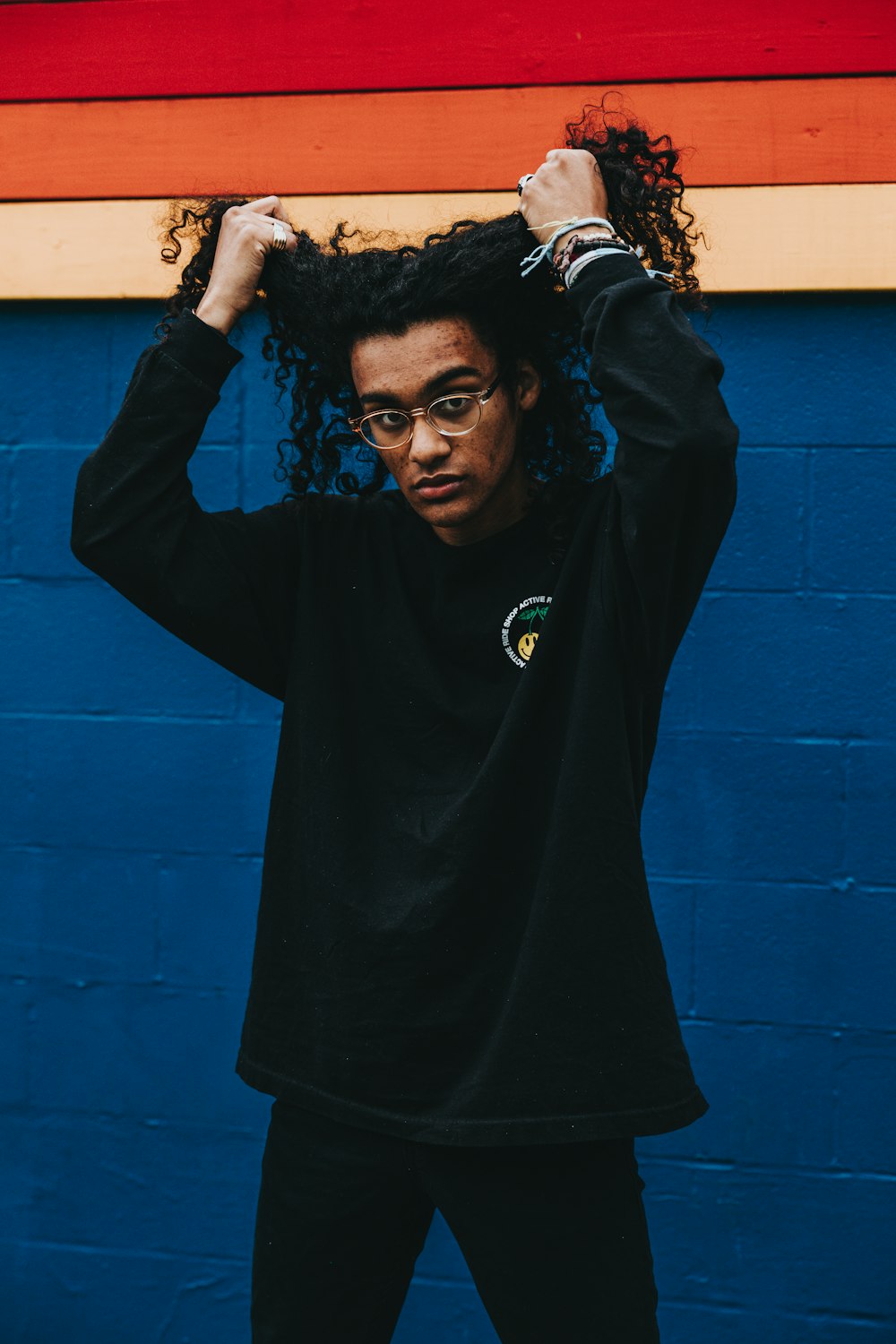 man holding his hair beside blue wall