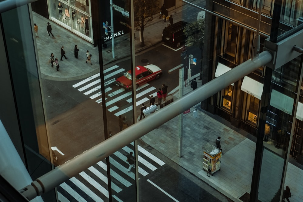 photography of people walking on street reflected on building window