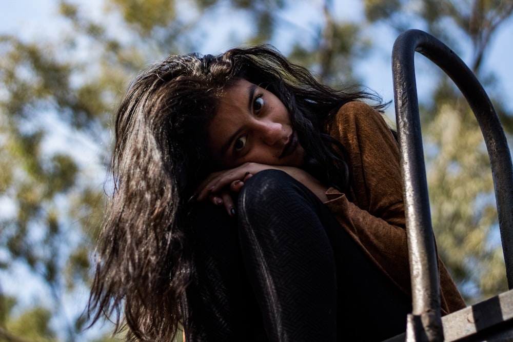 selective focus photography of woman sitting near gray metal ladder