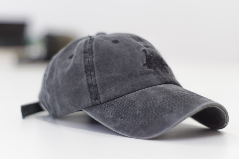 gorra de béisbol gris sobre superficie blanca