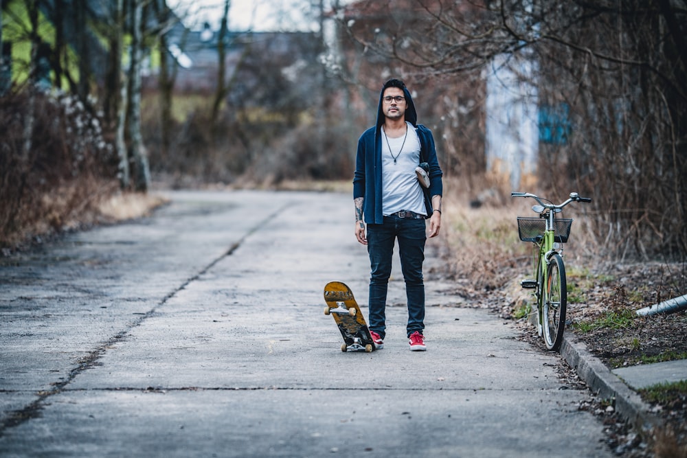 Uomo che gioca uno skateboard accanto alla bicicletta verde della città