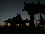 Golden temple bells hanging gracefully against a saffron sky at dawn.