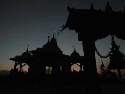 Golden temple bells hanging gracefully against a saffron sky at dawn.
