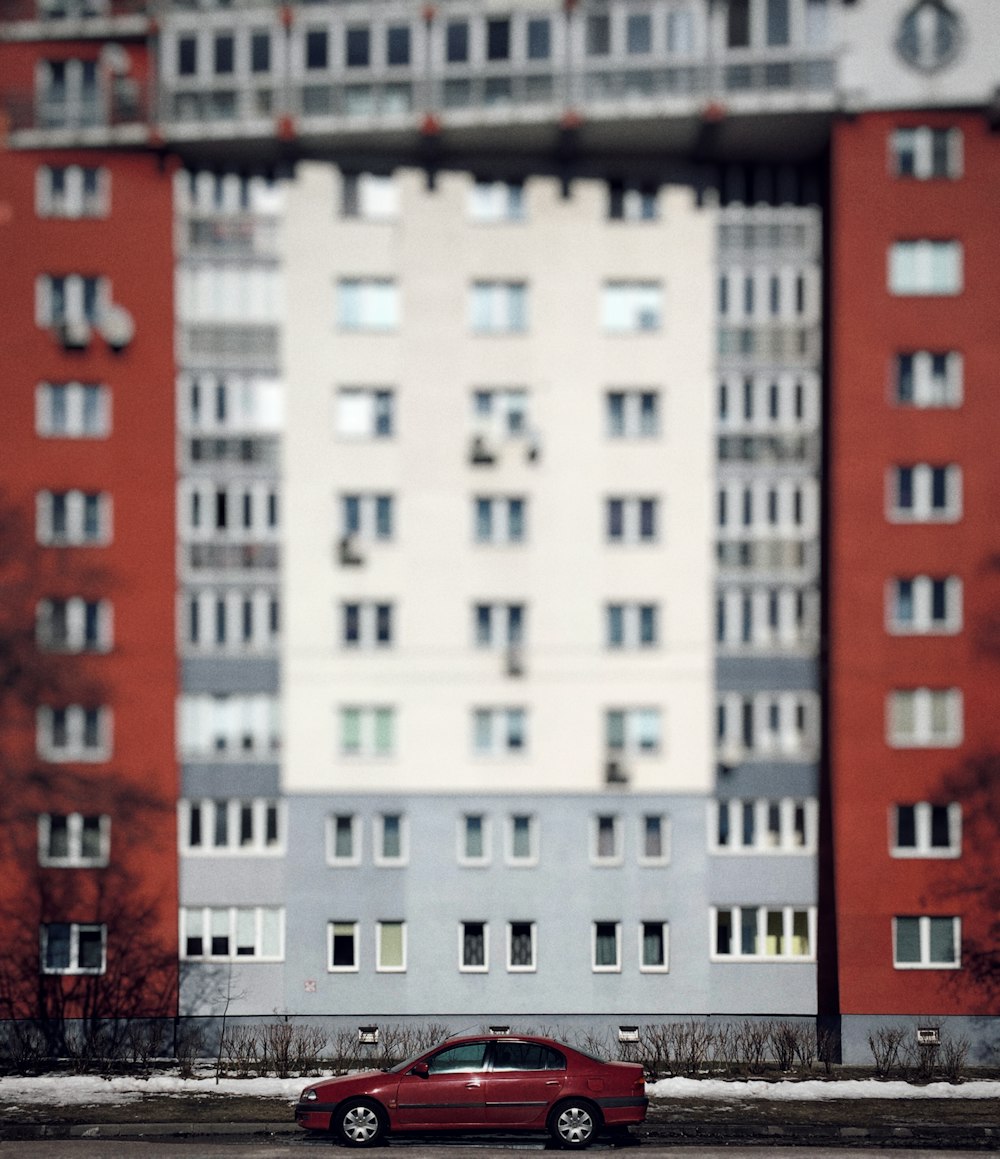 Parque de sedán rojo en frente en un edificio de hormigón