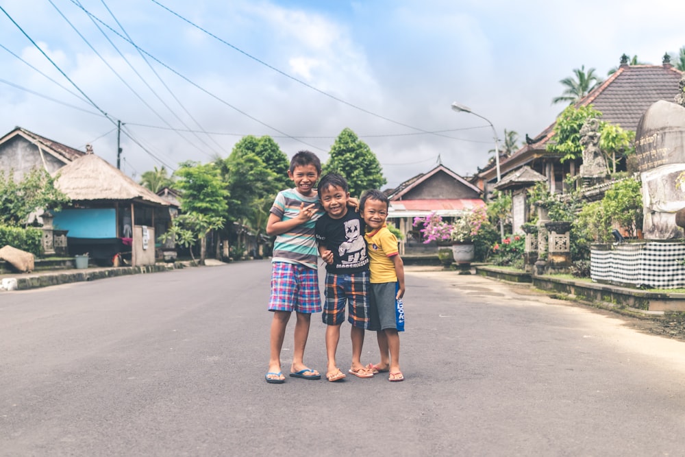 three boy standing on road