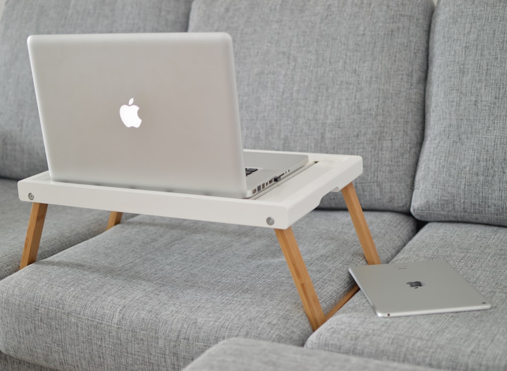 silver MacBook on laptop table on sofa
