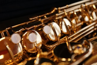 Close-up view of a brass saxophone showcasing the intricate details of its keys and mechanisms. The instrument's shiny golden surface reflects light, highlighting the smooth texture and craftsmanship.