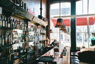 Cozy bar counter with warm lighting and bottles neatly arranged on shelves.