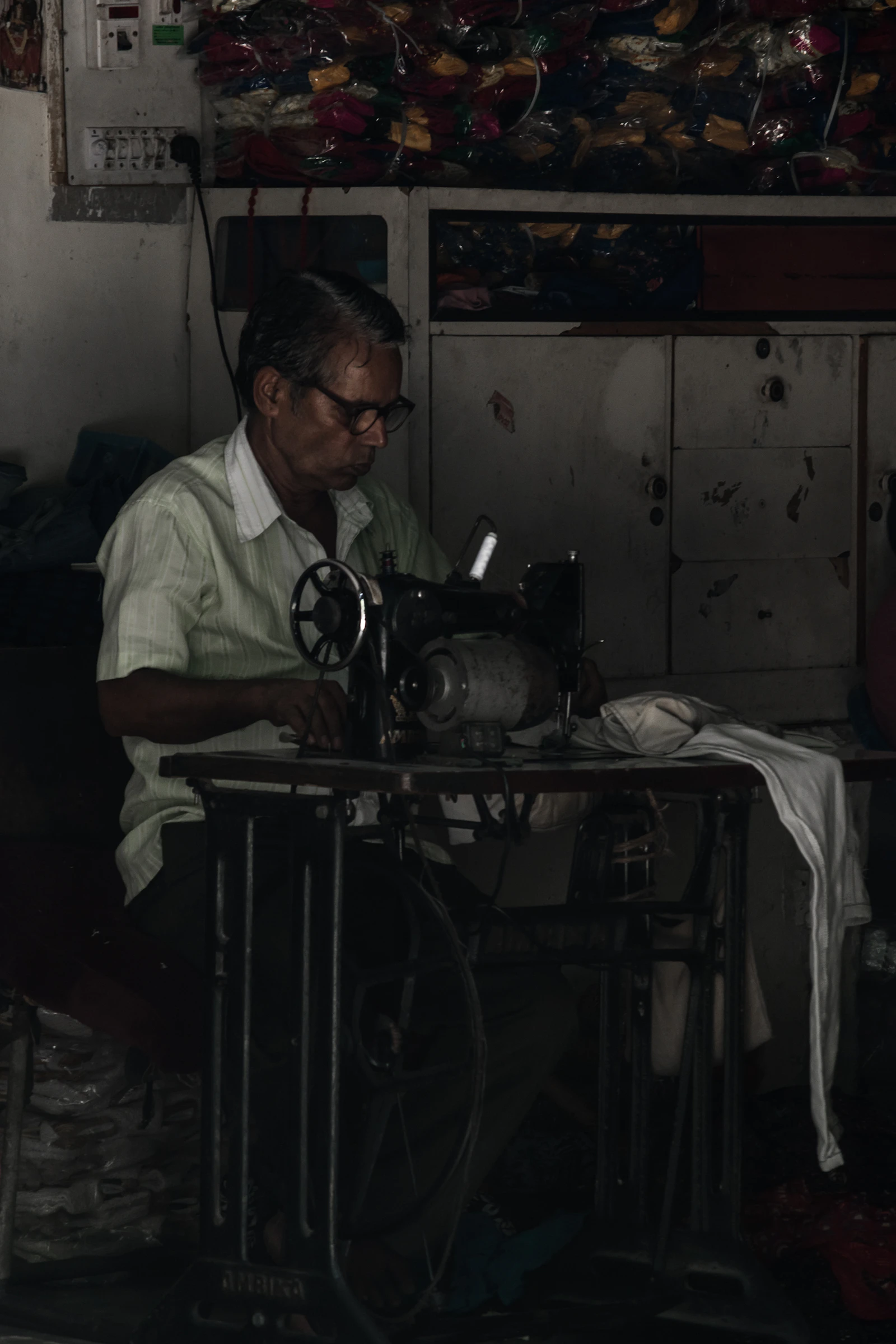 A tailor seated at a sewing machine working on a garment