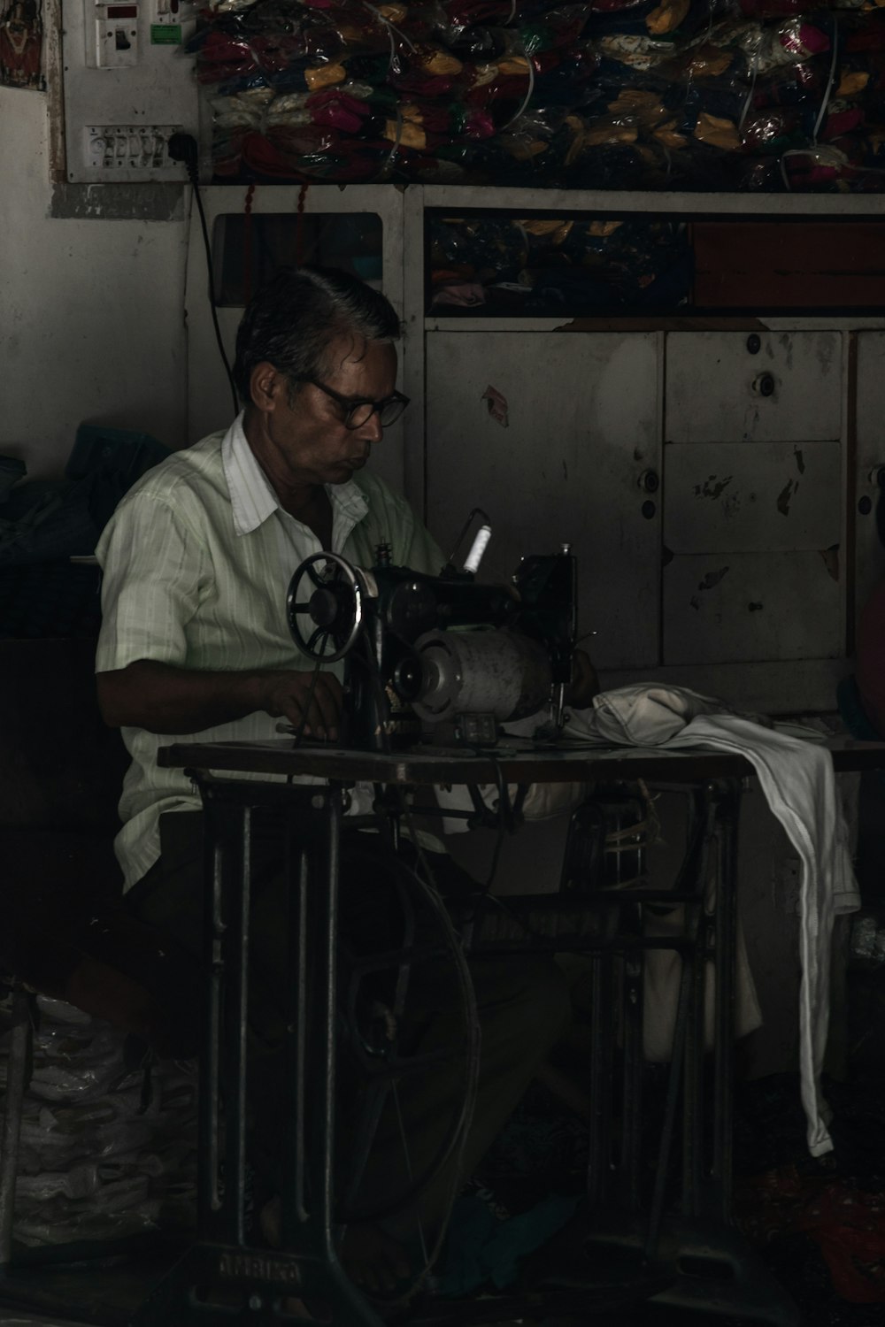 Mann sitzt auf Stuhl und arbeitet an der Nähmaschine