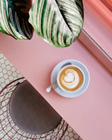 cup of coffee on saucer with teaspoon on pink tabletop