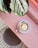 cup of coffee on saucer with teaspoon on pink tabletop