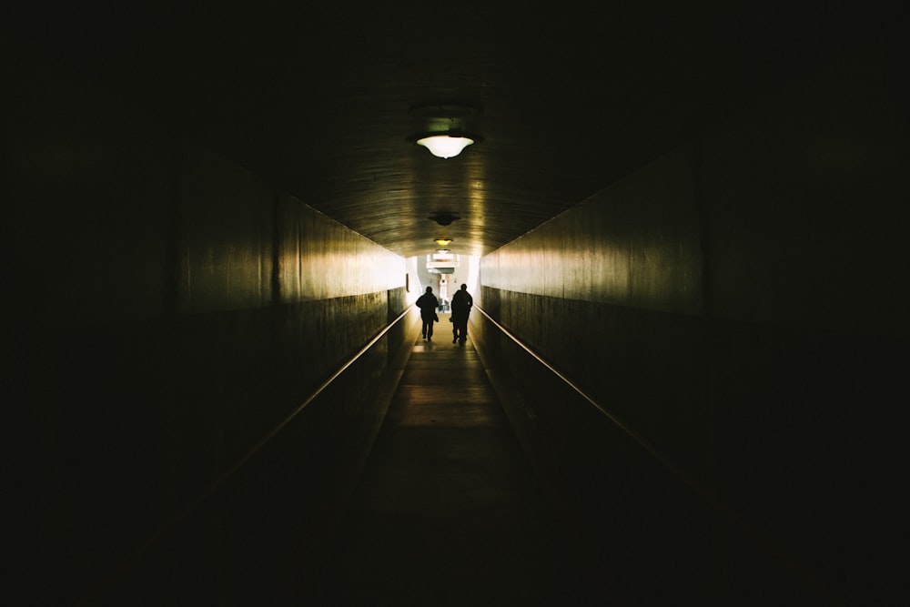 duas pessoas caminhando entre paredes de concreto