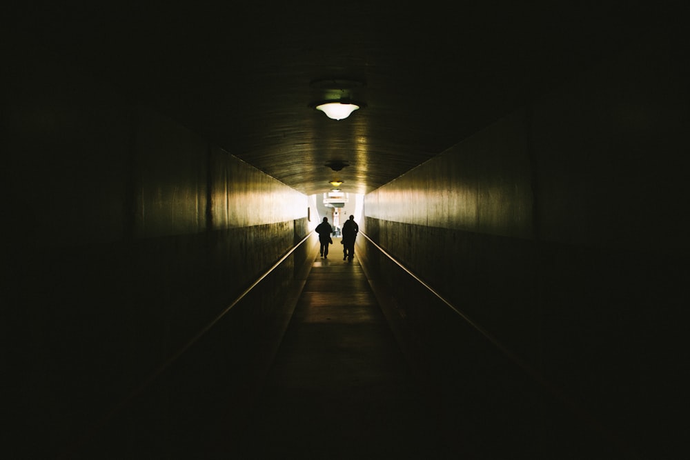 two person walking between concrete walls