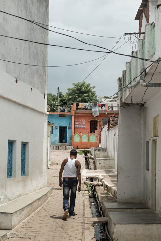 man walking in narrow pathway at daytime in Orachha India