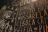 Chalkboard art features various words related to food, such as 'burger' and 'shake', surrounded by decorative drawings and abstract shapes. The text is written in large, bold letters with a hand-drawn, casual style.