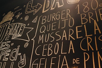 Chalkboard art features various words related to food, such as 'burger' and 'shake', surrounded by decorative drawings and abstract shapes. The text is written in large, bold letters with a hand-drawn, casual style.