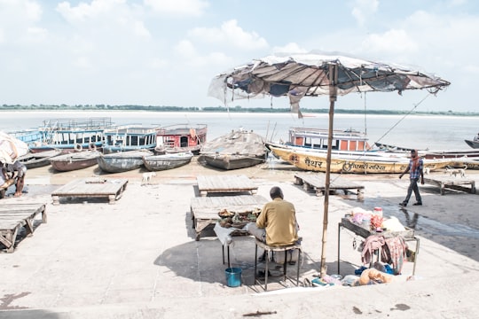 photo of man under patio umbrella near body of water in Varanasi India