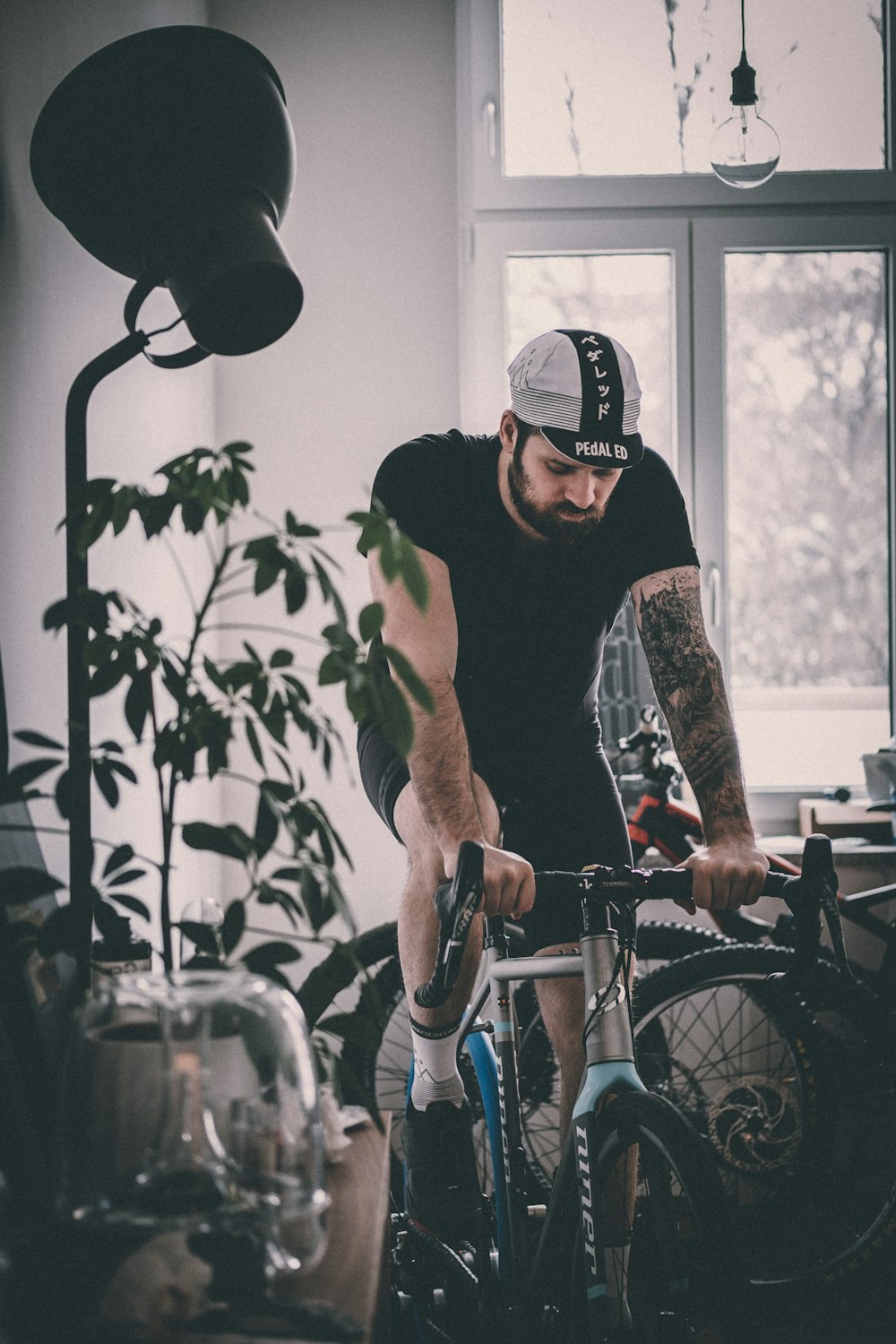 man riding on gray rigid bicycle near window