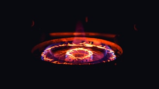 A burning stove top radiating bright orange and red flames with a glowing pattern, creating a warm and intense glow against a dark background.