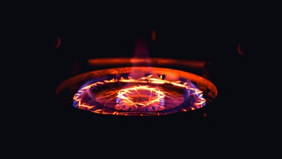 A burning stove top radiating bright orange and red flames with a glowing pattern, creating a warm and intense glow against a dark background.