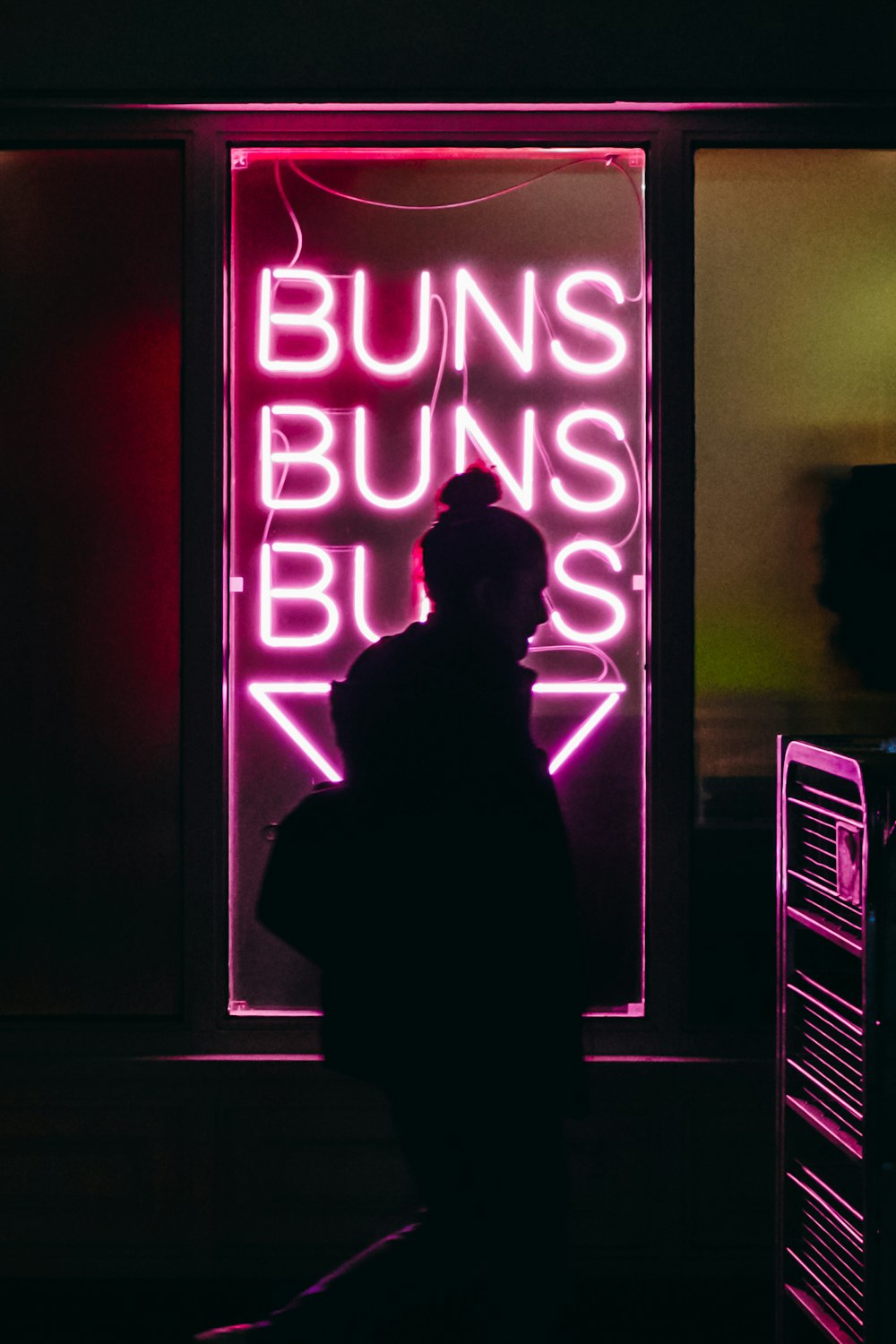 woman standing in front of BUNS LED signage