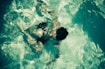 man swimming in green body of water