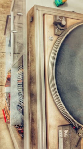 Vinyl records stacked beside a vintage reel-to-reel tape recorder.