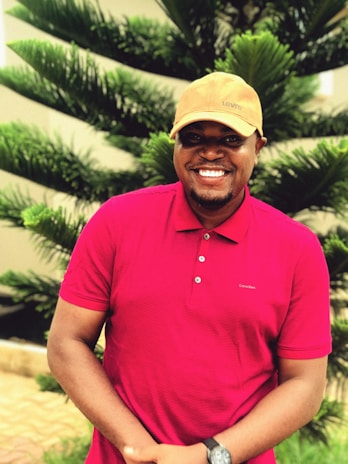 A happy customer wearing a red striped polo shirt, smiling outdoors on a sunny day.