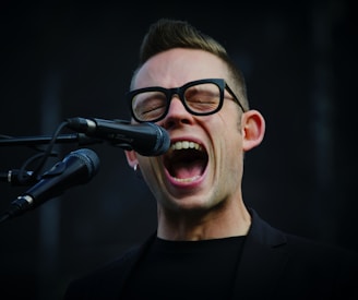 shallow focus photography of man shouting using microphone