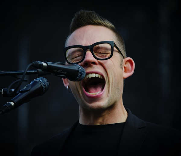 shallow focus photography of man shouting using microphone