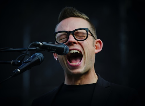 shallow focus photography of man shouting using microphone
